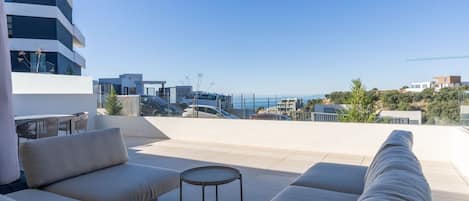 Una terraza en la azotea con un conjunto de sofás, una mesita redonda y vistas de la ciudad.