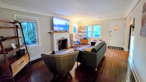 A living room with a fireplace, a television, a sofa, a chair, and a bookshelf. - ​The Seattle Scenes House: 5-Suite Boutique Home near Light Rail (Seattle)