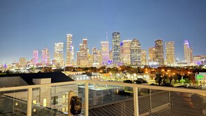 Terraço no topo com vista para o horizonte urbano, guarda-corpos de vidro e um alto-falante.