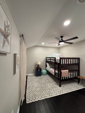 A bedroom with a bunk bed, a ceiling fan, a bedside lamp, and a patterned rug. - 4-bedroom house with beautiful backyard patio perfect for relaxing stays. (Frankford)