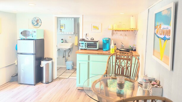A compact kitchen with a refrigerator, microwave, and toaster. A dining table with chairs is in the foreground. - Cozy 1 bed/1 bath two blocks from beach and boards (North Wildwood)