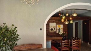 A dining area with a chandelier, wooden benches, and a stone floor. - Lindengut (Natternbach)