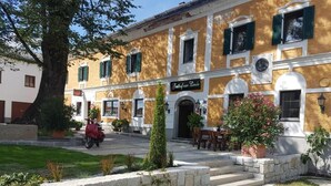 A building with a sign reading 'Hotel de la Lune.' It features a stone wall, a paved entrance, and outdoor seating. - Lindengut (Natternbach)