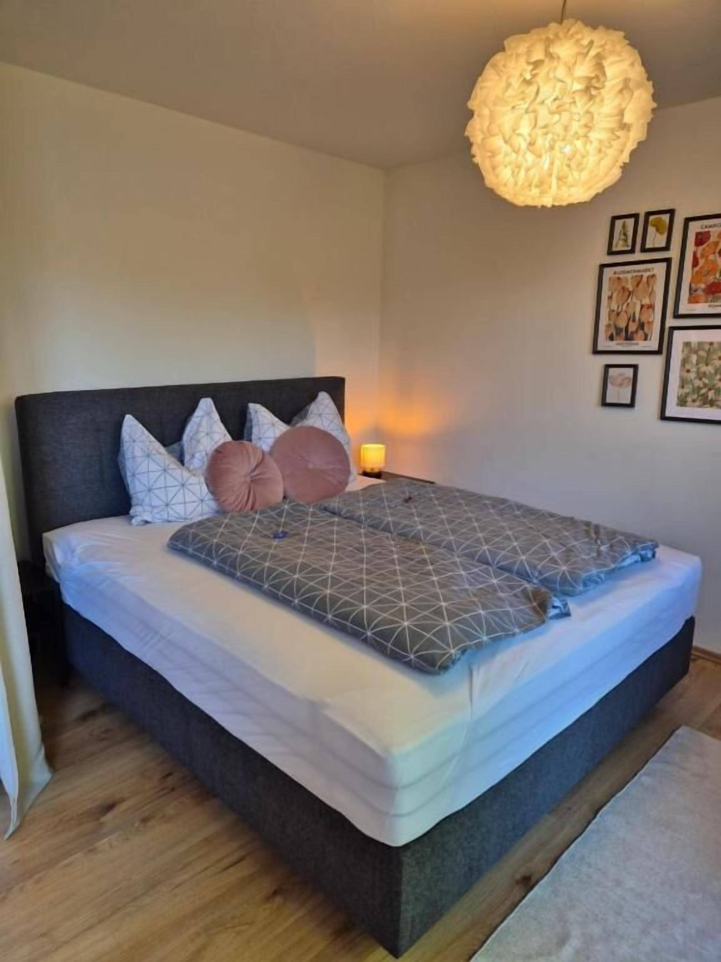 Una camera da letto con un letto, cuscini, una lampada da comodino e decorazioni alle pareti.