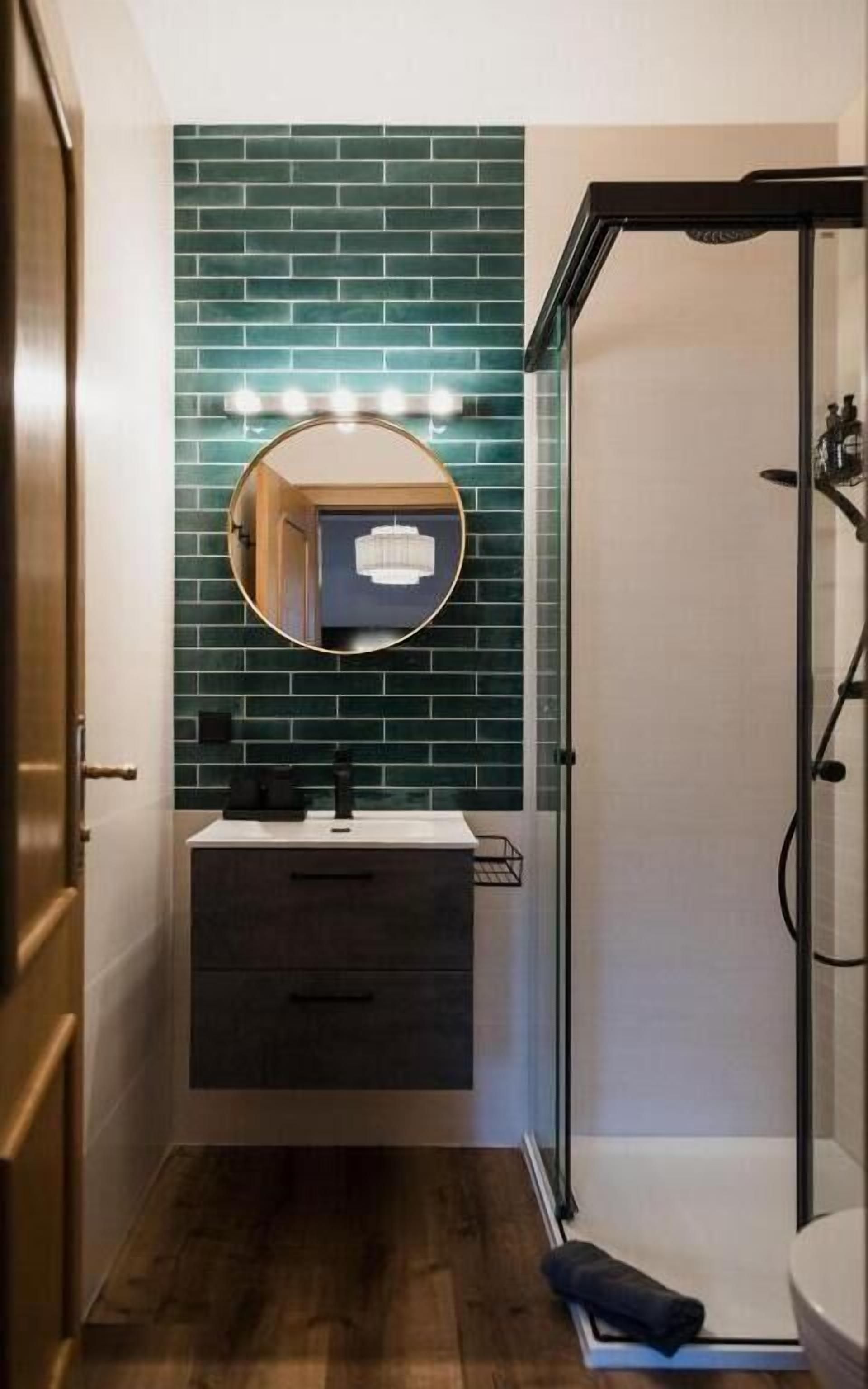 A bathroom with a mirror, vanity, and a shower.