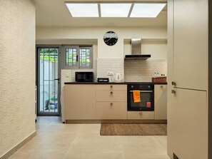 A modern kitchen with a microwave, kettle, and oven. - Vibrant Flat in Voula Center (Voula)