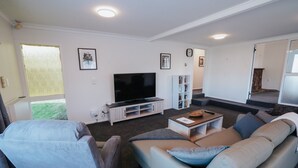 En stue med fjernsyn, sofa og bogreol.