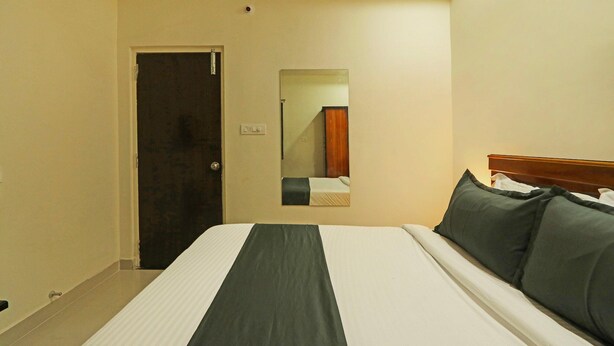Quarto de hotel com uma cama, uma porta e um espelho na parede.