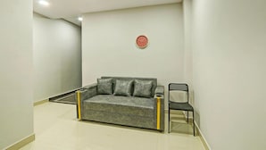 Quarto moderno com um sofá cinzento, uma cadeira preta e um relógio de parede vermelho.