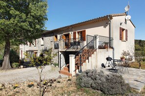 Une maison à deux étages avec une façade en pierre, un balcon et une antenne parabolique.