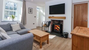 Ein Wohnzimmer mit Kamin, einer Couch, einem Couchtisch und einem an der Wand befestigten Fernseher.