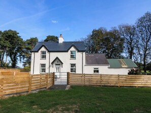 A two-story house with a front door, windows, and a small attached garage. - Gate House (Llangefni)