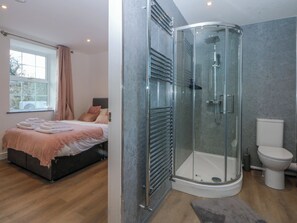 A modern bedroom with a bed, a bedside table, and a window. - Gate House (Llangefni)