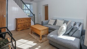 Ein Wohnzimmer mit Treppe, einem grauen Sofa, einem Holztisch und einem Schrank.