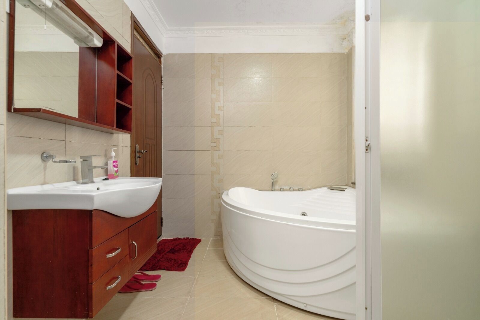Un bagno con lavandino bianco, mobile contenitore in legno e vasca da bagno.