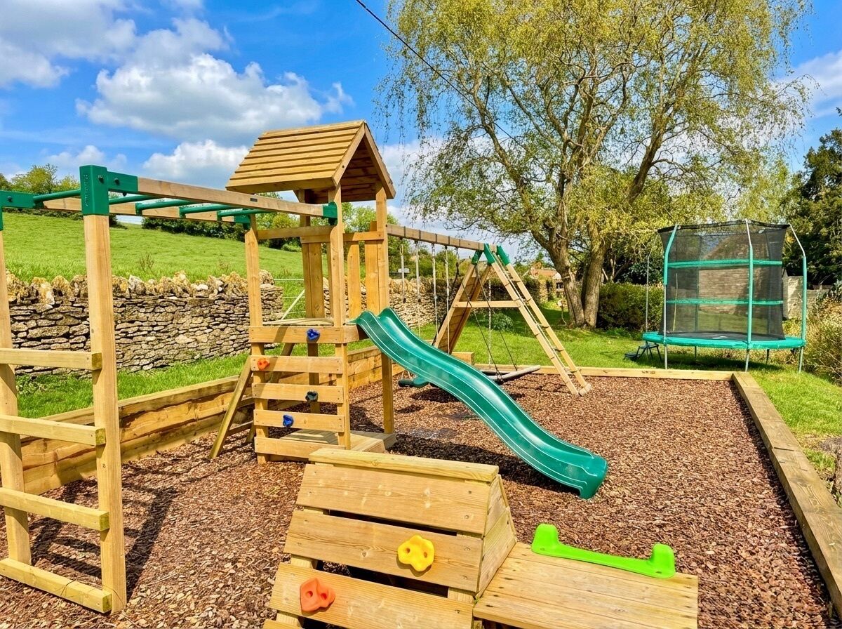 Un parque infantil con un tobogán de madera, estructuras para escalar y una casita.