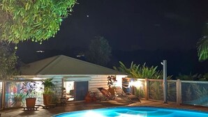 Ein Pool mit Liegestühlen, einer überdachten Terrasse und Kübelpflanzen.