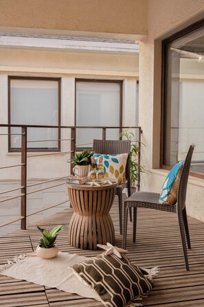 A balcony with a wicker chair, a small round table with a plant, and a potted plant on the floor. - Staymaster Casa Mancurad 3BR Villa  (Vagator)