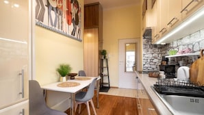 A compact kitchen with a dining area, a stone backsplash, and a modern stove. - Malila Premium Apartments Traugutta (Kraków)