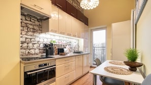 A modern kitchen with a stone backsplash, stainless steel appliances, and a dining area with a table and chairs. - Malila Premium Apartments Traugutta (Kraków)