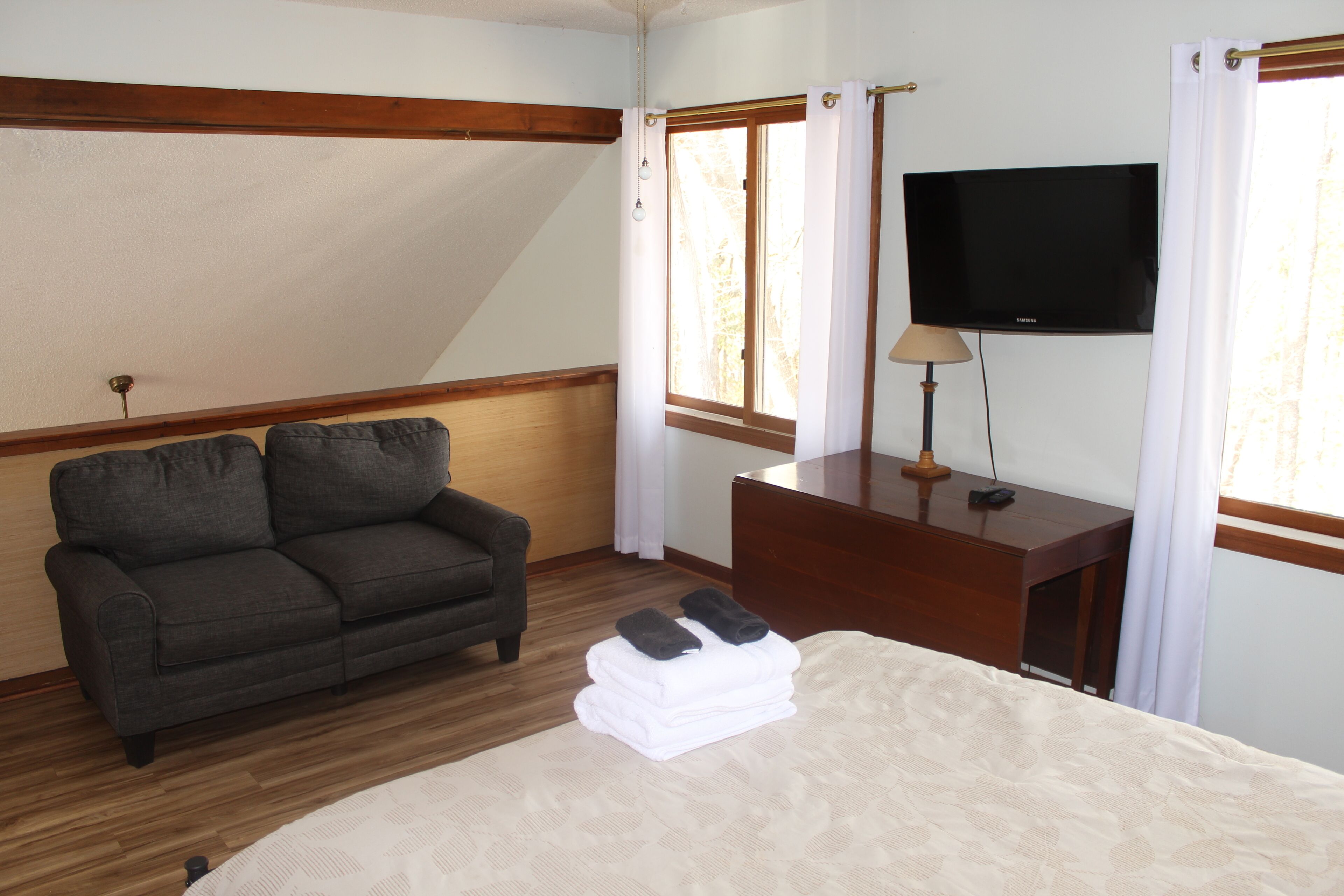 Une chambre d’hôtel avec un lit, un canapé, une télévision et un bureau.