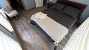 A bedroom with a bed, a chair, a bedside table, and a door. - cabañas entre sauces (Coyhaique)