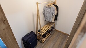 A small room with a wooden shoe rack, a hanging clothes rack, and a suitcase. - cabañas entre sauces (Coyhaique)