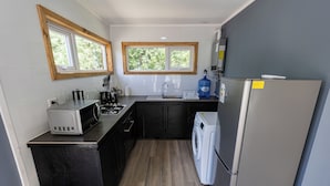A compact kitchen with a microwave, sink, and washing machine. - cabañas entre sauces (Coyhaique)