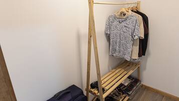 Una habitación con un zapatero de madera, un perchero y una maleta.