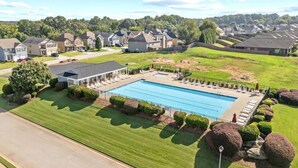 Ett bostadsområde med en swimmingpool, välskötta gräsmattor och hus i bakgrunden.