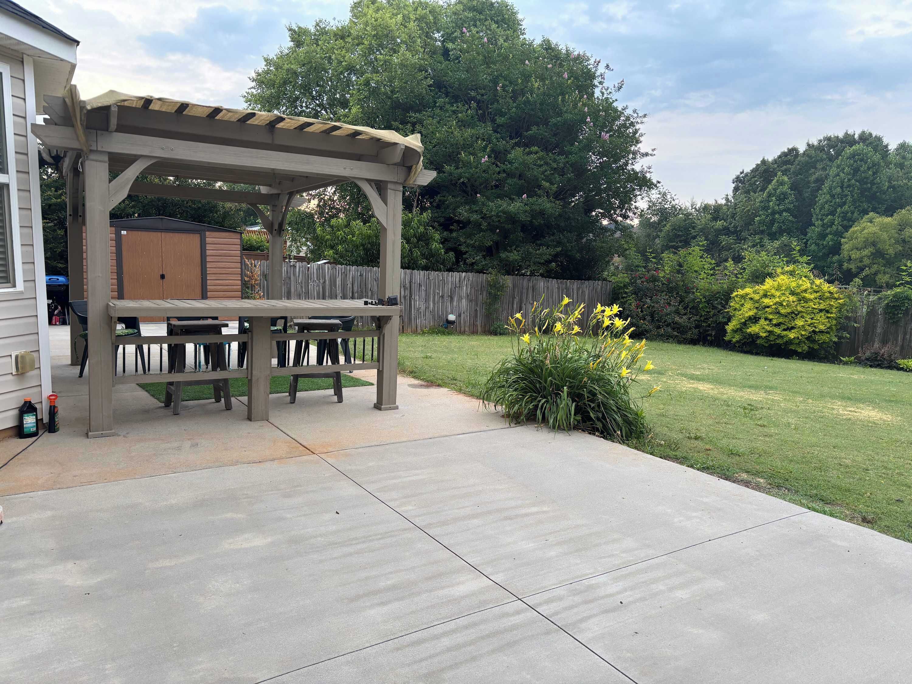 A patio with a pergola, a table, and chairs.