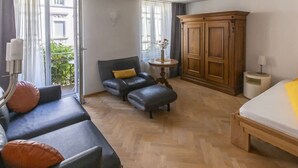 Een kamer met een bank, een poef, een houten kast en een bed.