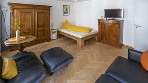 Een kamer met een bed, een televisie, een kast, een tafel met een vaas en twee banken.