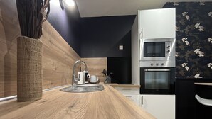A modern kitchen with a wooden countertop, stainless steel appliances, and a black backsplash. - Charming apartment in the heart of the city center – 2 guests (Angers)