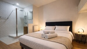 A modern hotel room with a large bed, a walk-in shower, and a bedside table with a lamp. - Charming apartment in the heart of the city center – 2 guests (Angers)
