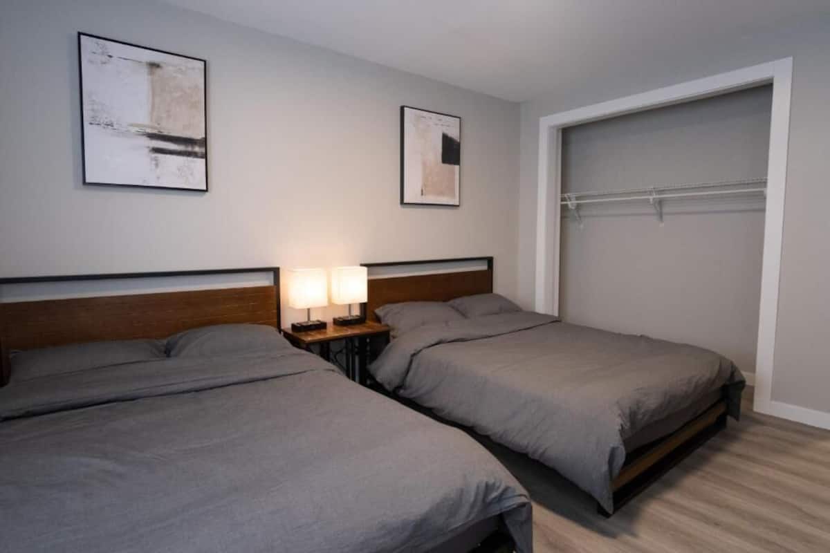 Habitación de hotel con dos camas, una mesita de noche con lámparas, un armario y dos obras de arte enmarcadas en la pared.