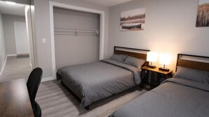 A bedroom with two beds, a desk, and a chair. There is a door leading to another room. - CK Motel (Chatham)