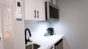 A kitchen with a built-in microwave, a coffee maker, and a stainless steel sink. - CK Motel (Chatham)