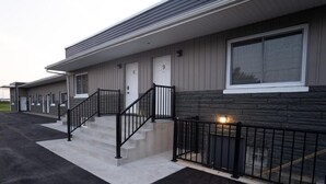 A building with a staircase leading to a door marked with the number 9, a black metal railing, and a stone facade. - CK Motel (Chatham)