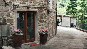 A stone building with a wooden door, a signboard, and flower pots. - Historical suite for writers and hikers (Toscana)
