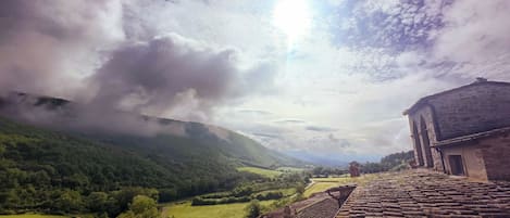 A rural landscape with a stone building, a path, and a valley.