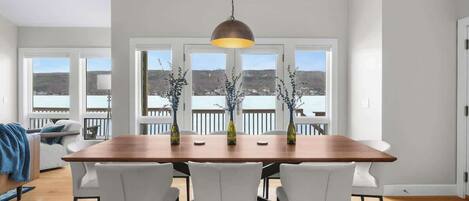 A dining area with a wooden table, white chairs, and a hanging pendant light.