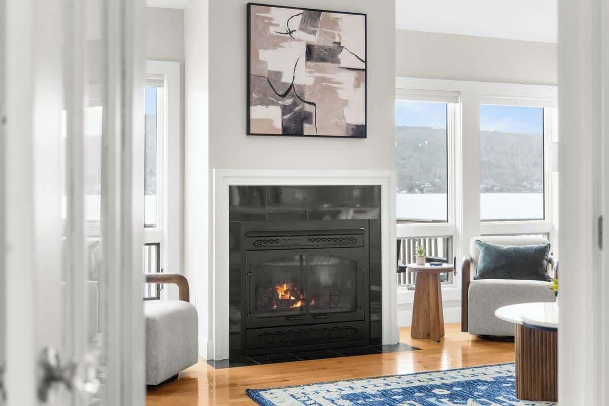 A living room with a fireplace, a sofa, a coffee table, and a view of the outdoors.