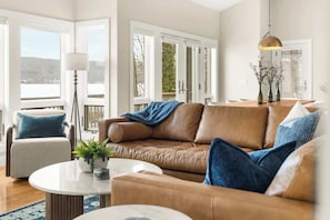 Ein geräumiges Wohnzimmer mit einem braunen Ledersofa, einem runden Couchtisch und einem blauen Sessel.