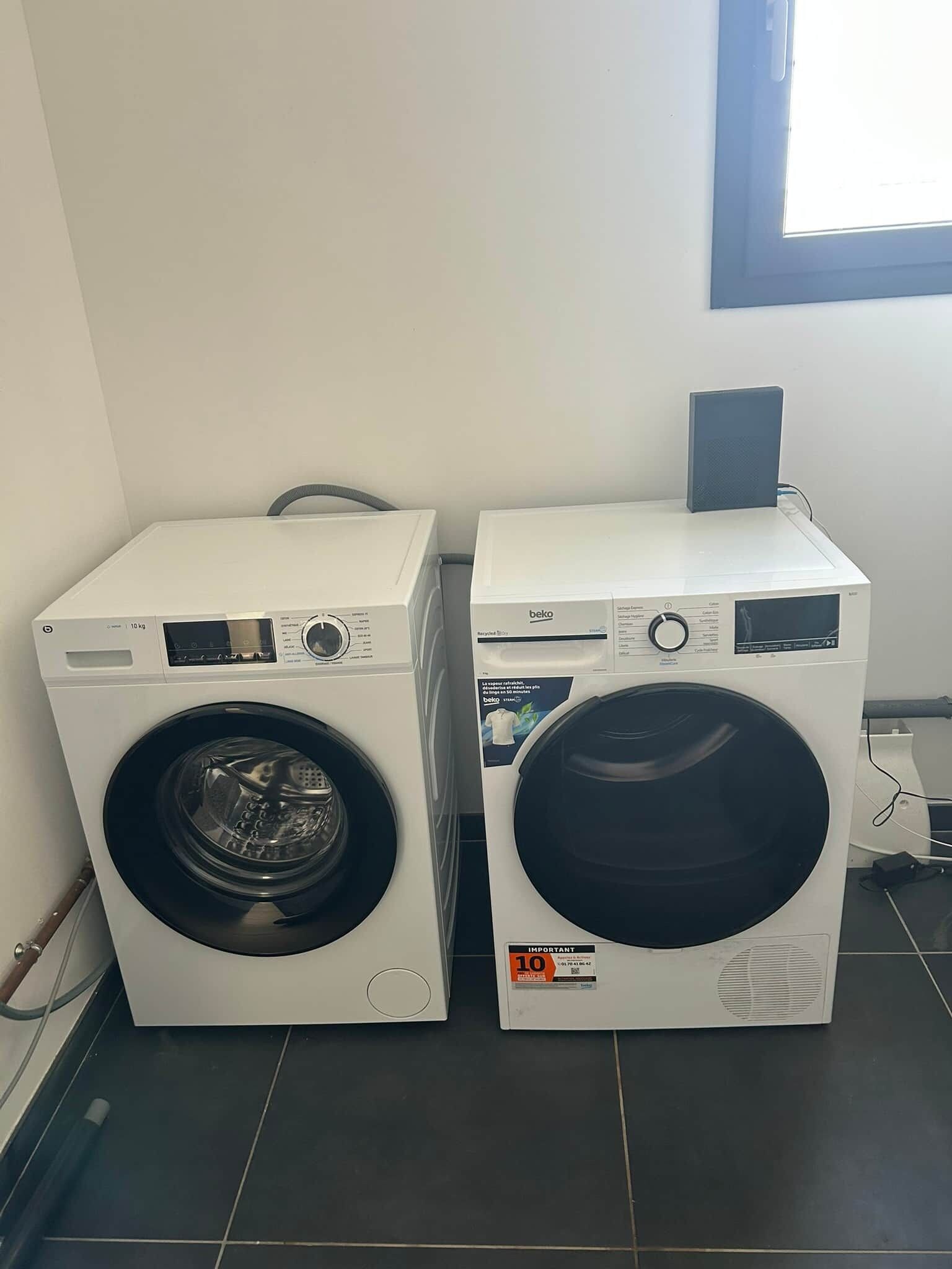 Two front-loading washing machines side by side in a room with a window and tiled floor.
