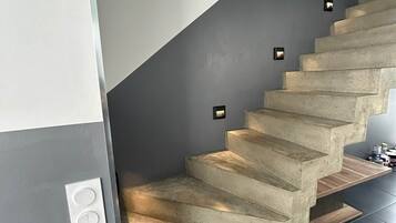 Een betonnen trap met ingebouwde verlichting, die naar een donkere verdieping leidt.