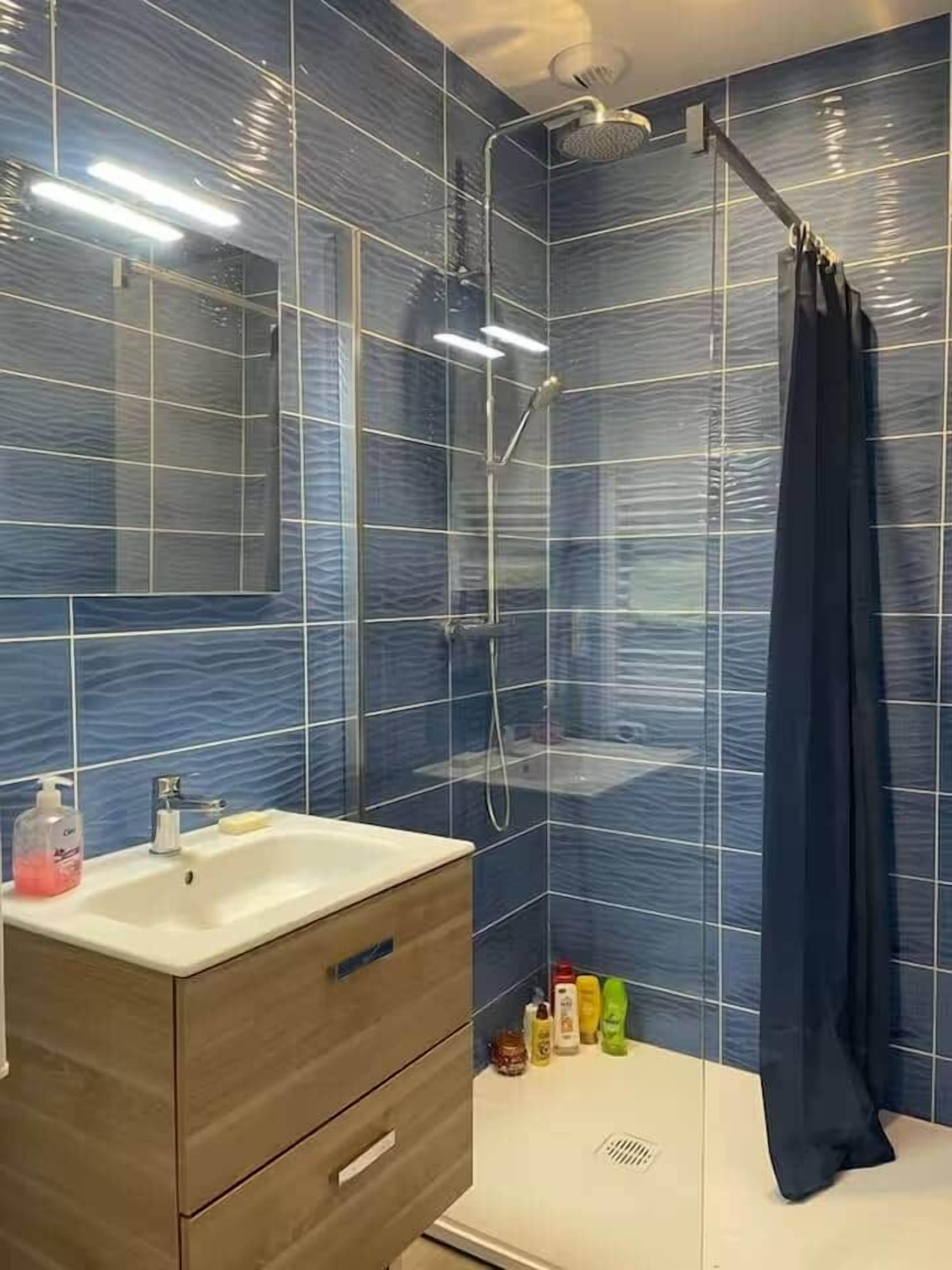 Een moderne badkamer met een douche, een wastafel en een spiegel.