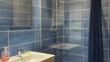 Een moderne badkamer met een douche, een wastafel en een spiegel.
