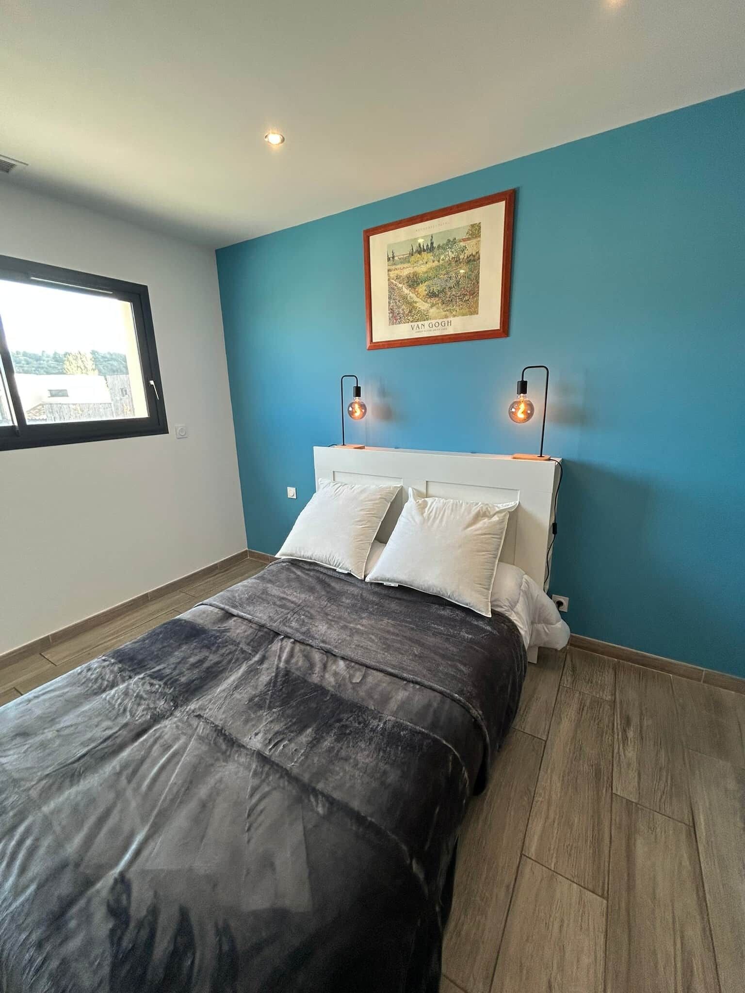 Un dormitorio con una cama, dos lámparas de noche, un cuadro enmarcado y una ventana.