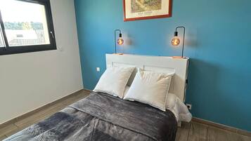Un dormitorio con una cama, dos lámparas de noche, un cuadro enmarcado y una ventana.
